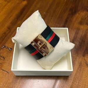 Bracelet with black-red & green stripe down the middle. Gold tone lock closure